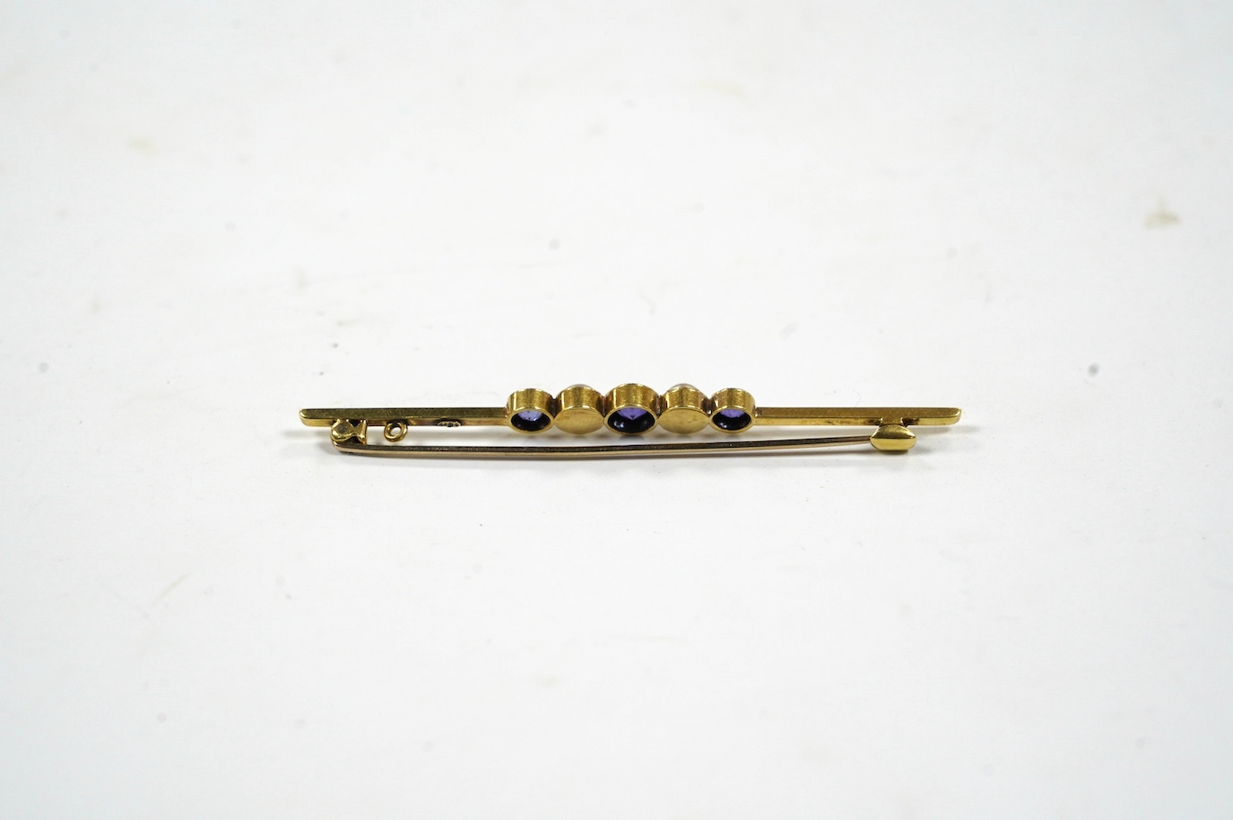An Edwardian 15ct, three stone sapphire and two stone split pearl set bar brooch, 64mm, gross weight 3.4 grams. Condition - fair to good